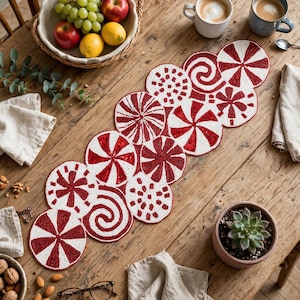 May include: A beaded table runner featuring a repeating pattern of circular red and white peppermint candy designs, including swirls, starbursts, and striped motifs, arranged in an elongated, interconnected cluster across the surface.
