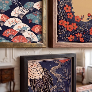 Può includere: Tre stampe d'arte incorniciate con illustrazioni dettagliate. Una stampa mostra un motivo di ventagli pieghevoli, un'altra fiori rossi su una grande luna pallida e la terza raffigura una gru con elementi floreali in una tonalità blu scuro.