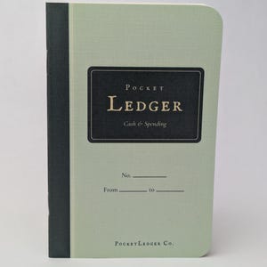 May include: A light green pocket ledger notebook with a black spine and a black rectangular label on the front cover. The label features the text Pocket Ledger and Cash & Spending in white and gold, with lines for No., From, and to.