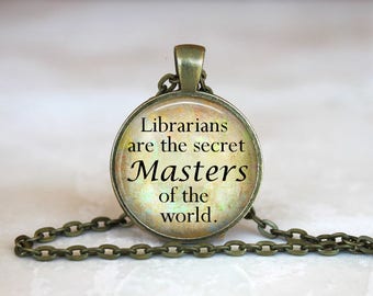 May include: A bronze necklace with a round pendant featuring a quote that reads "Librarians are the secret Masters of the world."