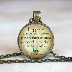 May include: A bronze necklace with a glass pendant featuring a quote from Albus Dumbledore: "Happiness can be found, even in the darkest of times, if one only remembers to turn on the light." - Dumbledore