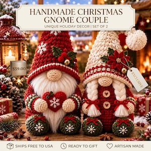 May include: A pair of handmade crochet Christmas gnomes. The left gnome wears a red hat with a white snowflake and holly, holding a red heart. The right gnome wears a cream hat with a poinsettia and has white braided hair with two buttons.
