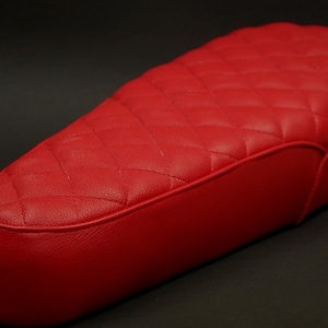 Puede incluir: Asiento de motocicleta acolchado rojo con forma curva.