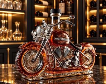Puede incluir: Un decantador de cristal con forma de motocicleta lleno de líquido ámbar. El depósito de combustible lleva el logotipo de Harley-Davidson Motor Company. La base es de cristal transparente con el nombre Harley-Davidson en negro.