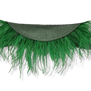 May include: A green straw hat with a wide brim and a feather trim.