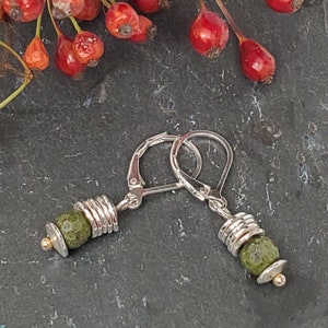 May include: Silver earrings with green gemstone beads and gold accents.