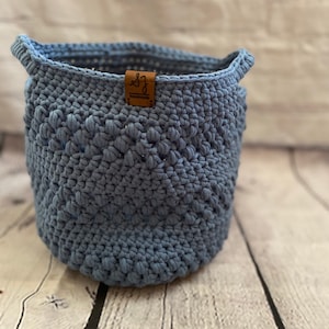 May include: A blue crocheted storage basket with a brown leather tag that says "SJ Handmade".