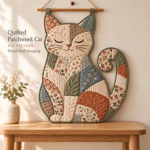 May include: A quilted patchwork cat wall hanging featuring floral and striped fabric patterns in muted tones of rust, blue, and cream. The cat has closed eyes and is suspended from a wooden rod. Text reads: Quilted Patchwork Cat PDF PATTERN Floral Wall Hanging.