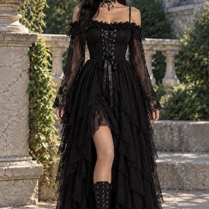 Puede incluir: Un vestido negro largo hasta el suelo con corpiño de corsé con cordones, mangas largas de encaje transparente que dejan los hombros al descubierto y una falda de volantes escalonados con dobladillo asimétrico, junto a gargantilla y botas.