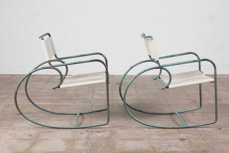 Op de afbeelding: Twee vintage schommelstoelen met een lichtblauw metalen frame en witte gevlochten zittingen.