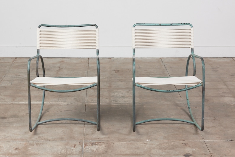 Op de afbeelding: Twee stoelen met een witte gevlochten zitting en rugleuning en een lichtblauw metalen frame.