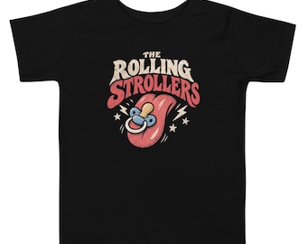 May include: A black short-sleeve t-shirt featuring a graphic print with the text THE ROLLING STROLLERS in white and red. The design includes a large pink tongue with a blue and white baby pacifier, surrounded by small white stars and lightning bolts.