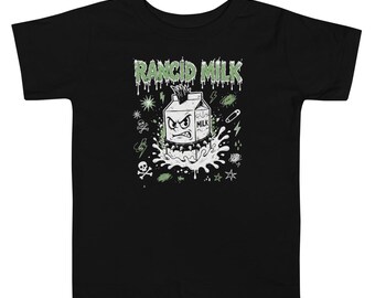 May include: A black short-sleeve t-shirt featuring a graphic of an angry milk carton character with a mohawk and spiked collar. The text RANCID MILK appears in a dripping green font above the carton, surrounded by small skull, star, and lightning bolt icons.