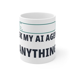 May include: A white ceramic mug featuring a dark teal command line interface graphic at the top. Below the graphic, the text reads ASK MY AI AGENT ANYTHING in bold, dark navy blue capital letters, centered on the front of the cylindrical mug.