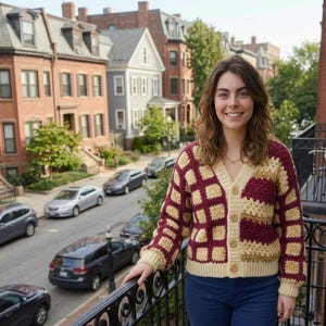 Peut inclure: Un cardigan à manches longues et col en V présentant un motif de carrés granny au crochet en blocs alternés de fil bordeaux foncé et crème, fini avec une fermeture boutonnée et des poignets et ourlet côtelés.