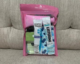 Peut inclure: Une pochette de voyage en plastique rose contenant un tube rose Spa Sciences, une brosse à dents jetable pré-imprégnée Guru Nanda, un sachet de bain de bouche Listerine Cool Mint, un petit flacon vert b-pure et un tissu à motifs bleus.