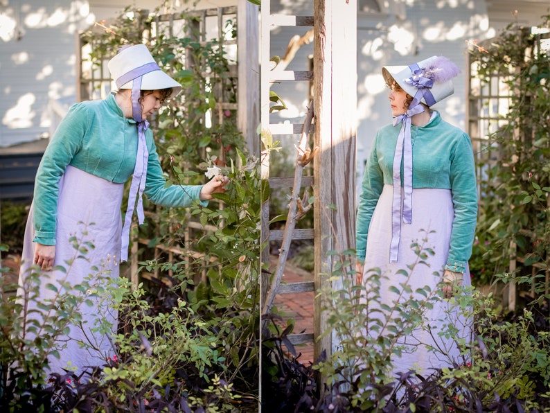 model wearing a turquoise velvet spencer over a lavender Regency dress and smelling a rose on a climbing rose bush