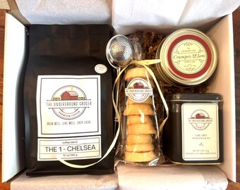May include: A gift box containing a 12 oz bag of The Underground Grocer coffee, a metal tea infuser, a clear bag of round cookies, a Crumpets & Jam candle in a glass jar, and a tin of The Underground Grocer Earl Grey premium black tea.