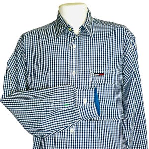 May include: A long-sleeve button-down shirt featuring a navy blue and white gingham check pattern. The shirt includes a pointed collar, a front button placket, and a single chest pocket adorned with a small rectangular red, white, and blue logo.