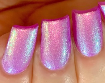 Puede incluir: Cuatro uñas pintadas con un esmalte de uñas morado claro con un brillo holográfico.