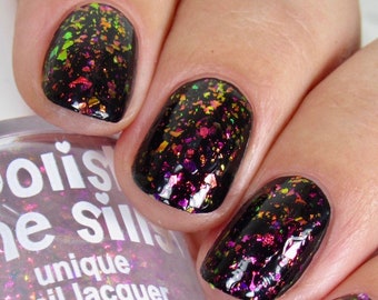 May include: A clear bottle of nail polish with a pink iridescent shimmer. The bottle is labeled "Polishes" and "Unique Nail Lacquer" with a 15 ml / 0.5 fl. oz. size. The bottle is shown with a hand wearing black nail polish with iridescent glitter.