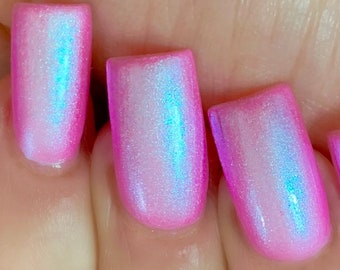 Puede incluir: Primer plano de cinco uñas pintadas con un esmalte de uñas rosa e iridiscente.