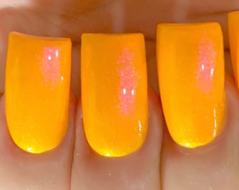 May include: Close-up of four fingernails painted with bright orange nail polish. The polish has a glossy finish with a subtle pink shimmer. The nails are neatly shaped and the skin around them is light-toned against a black background.