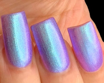 May include: Close-up of four fingernails painted with a light purple iridescent nail polish.