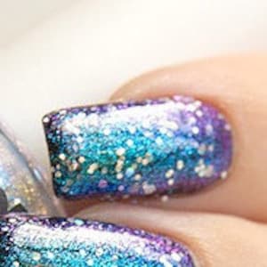 Puede incluir: Una botella de vidrio transparente de esmalte de uñas con un acabado de brillo plateado. La botella está etiquetada como "Polish Me Silly" y "Unique Nail Lacquer". La botella está junto a una mano con cuatro uñas pintadas con un esmalte de uñas de brillo azul y morado.