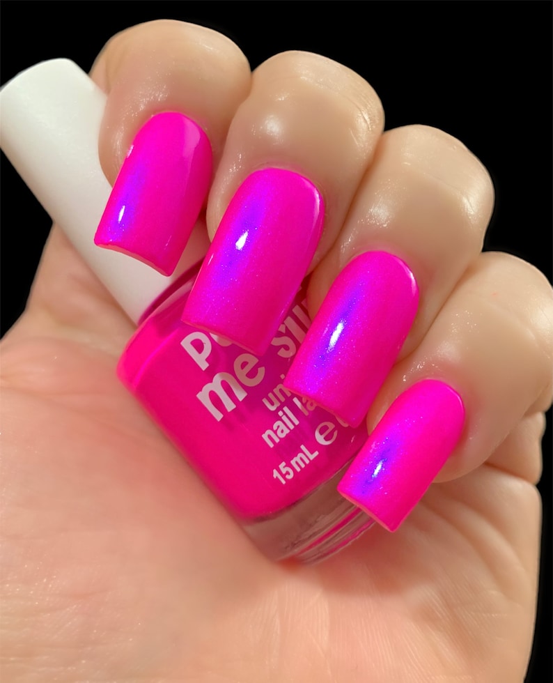 May include: A bottle of pink nail polish with a holographic finish. The bottle is labeled "Pop Me Shine" and "15mL e".