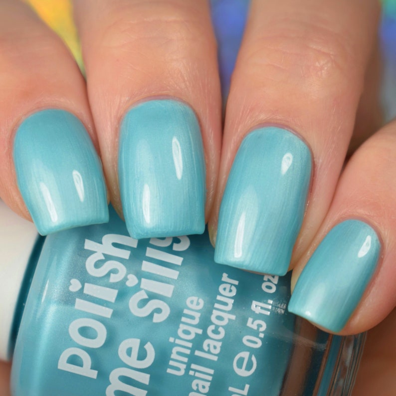 May include: A light blue nail polish bottle with the text "polish me silly" on the label. The bottle is 0.5 fl. oz. and is labeled as "unique nail lacquer".