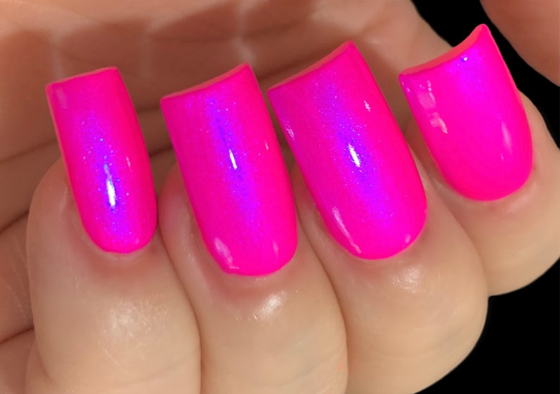 May include: Close-up of four fingernails painted with a bright pink nail polish with a holographic shimmer.