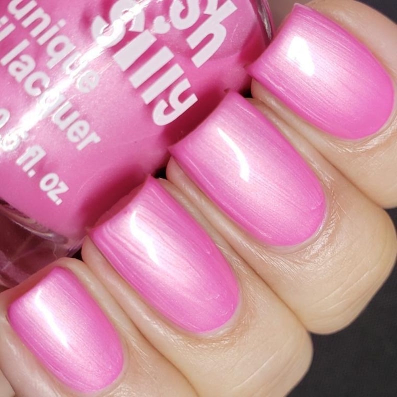 May include: Pink nail polish with a glossy finish. The bottle is labeled "Sally Hansen" and "Unique Lacquer".
