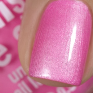May include: Close-up of a pink nail polish with a shimmery finish.