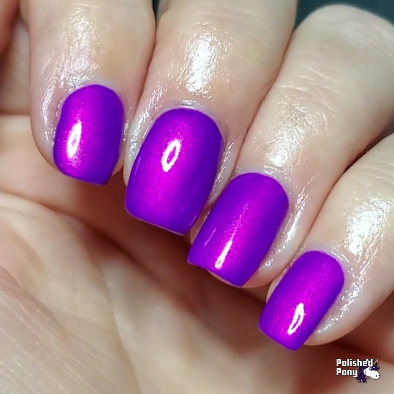 Puede incluir: Primer plano de una mano con cuatro u&ntilde;as pintadas con un esmalte de u&ntilde;as morado brillante y vibrante. El esmalte tiene un ligero brillo, que refleja la luz. Las u&ntilde;as est&aacute;n bien formadas y el color es consistente en todas las u&ntilde;as. La imagen est&aacute; bien iluminada.