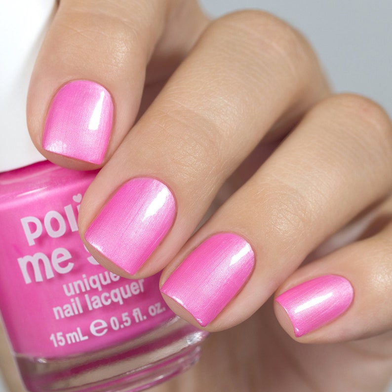 May include: Pink nail polish bottle with the text "Polished Me" and "unique nail lacquer" on the label. The bottle is 0.5 fl. oz. and contains a pink nail polish with a shimmery finish. A hand is shown with four fingernails painted with the pink nail polish.