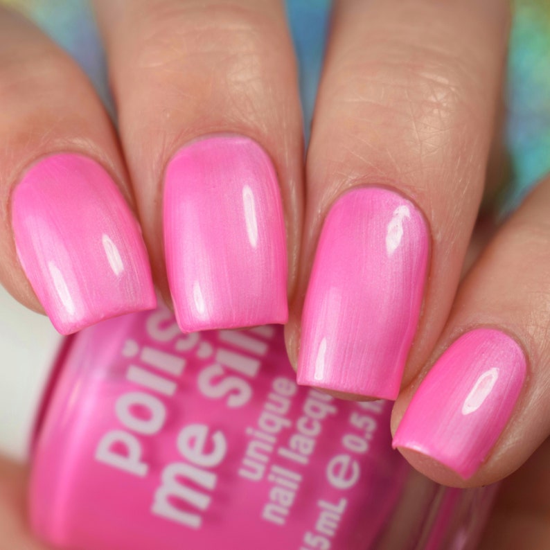 May include: Close-up of four fingernails painted with a bright pink nail polish. The nail polish bottle is visible in the foreground, with the brand name "polish me silly" and the text "unique nail lacquer" printed on the label.