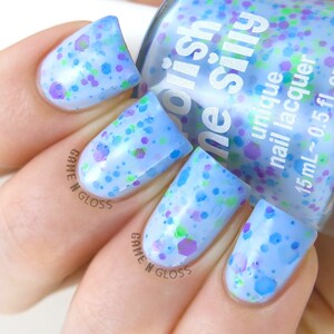 May include: A light blue nail polish with a clear base and multi-colored glitter. The bottle is labeled "Orish ne silly unique nail lacquer 15 mL~0.5 fl. oz".