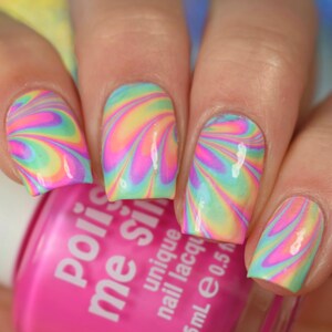 May include: Close-up of a hand with colorful swirl nail art. The nails are painted in a rainbow swirl pattern with pink, yellow, blue, and green colors. The hand is holding a pink bottle of nail polish with the text "Polished" and "Me Silly" on the label.