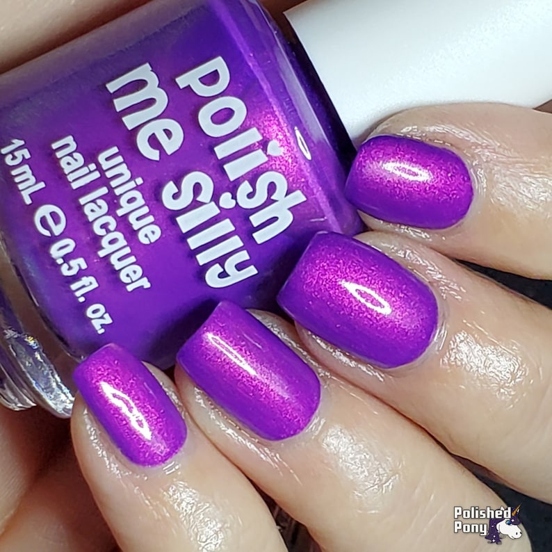 Puede incluir: Un frasco de esmalte de u&ntilde;as &uacute;nico 'Polish Me Silly' en un tono p&uacute;rpura vibrante, con el texto 'Polish me Silly' y 'unique nail lacquer' visibles. La imagen muestra u&ntilde;as pintadas del mismo tono, con un frasco de 15 ml.