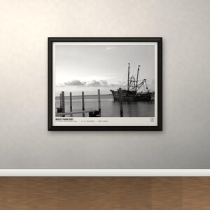 May include: A black and white framed print featuring a fishing boat docked near wooden pilings in calm water. The text "MOBILE FISHING BOAT" is printed at the bottom left of the image, along with additional small text and a square icon in the corner.