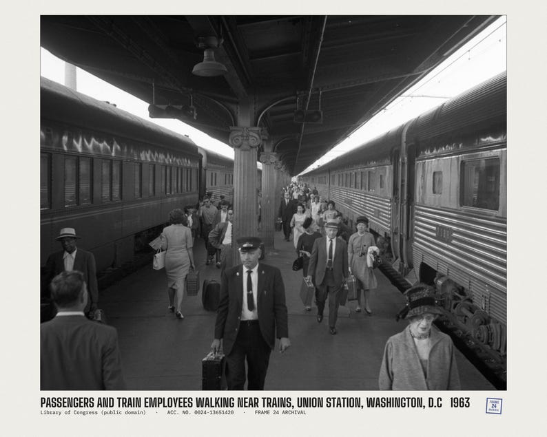 Peut inclure: Une photographie en noir et blanc montrant des passagers et des employ&eacute;s de train marchant sur un quai &agrave; Union Station, Washington, D.C. en 1963. Des personnes portent des bagages entre deux grands trains gar&eacute;s sous un toit de gare couvert.