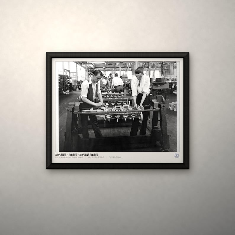 May include: A black and white framed photograph depicting two workers assembling an airplane engine in a factory setting. The print includes the text AIRPLANES - ENGINES - AIRPLANE ENGINES at the bottom, capturing a historical industrial scene.