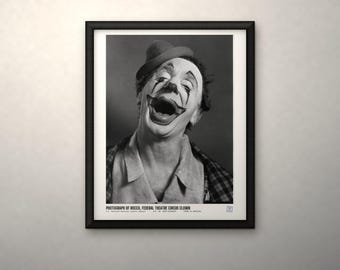 May include: A black and white framed photograph of a circus clown wearing a hat and a collared shirt. The clown has a wide, laughing expression with painted makeup. The text below reads: PHOTOGRAPH OF ROCCO, FEDERAL THEATRE CIRCUS CLOWN.