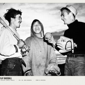 May include: A black and white photograph titled HOW TO PLAY BASEBALL featuring three individuals. One holds a wooden baseball bat, another holds a baseball, and the third wears a baseball glove. They are dressed in casual outdoor clothing.