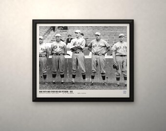 May include: A black and white framed photograph featuring five baseball players in Red Sox uniforms standing on a field. The text below the image reads: BABE RUTH AND OTHER RED SOX PITCHERS 1915. The frame is black with a white mat border.