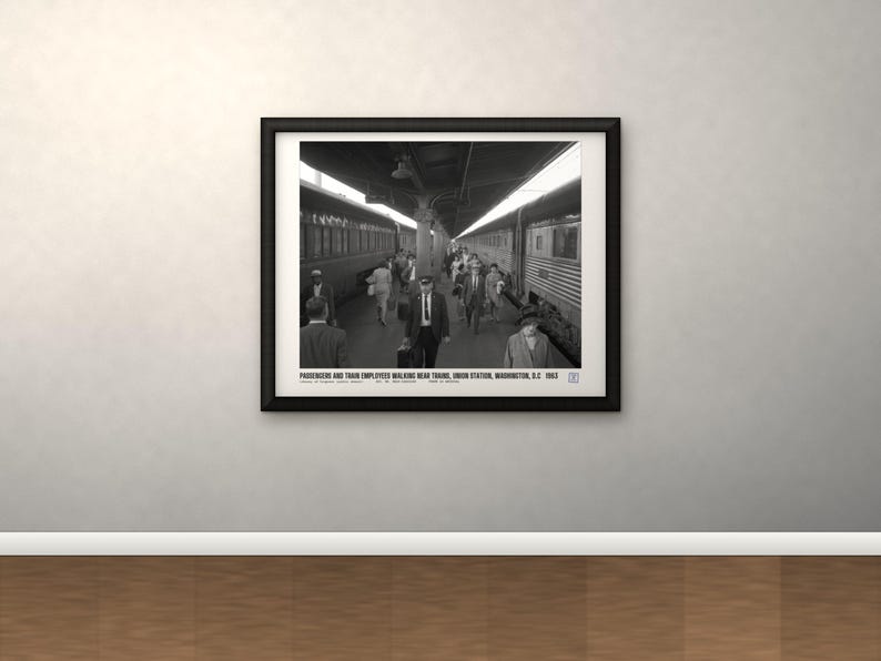 Peut inclure: Une photographie encadr&eacute;e en noir et blanc d'un quai de gare avec des passagers et des employ&eacute;s marchant pr&egrave;s des trains. Le texte en bas indique : PASSENGERS AND TRAIN EMPLOYEES WALKING NEAR TRAINS, UNION STATION, WASHINGTON, D.C. 1963.