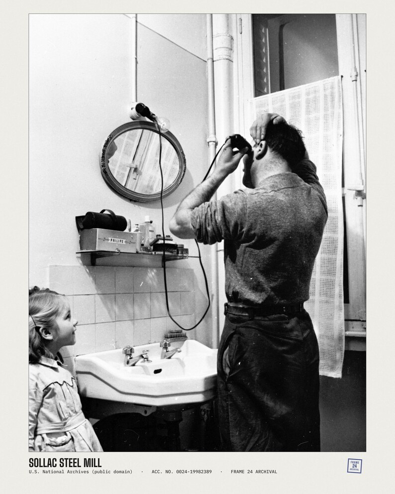 May include: A black and white photograph showing a person using an electric hair clipper in front of a bathroom mirror while a child watches. A shelf holds a box labeled PHILIPE, and the bottom text reads SOLLAC STEEL MILL.