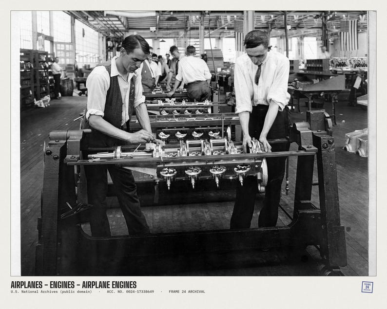 May include: A black and white archival photograph showing two individuals in a factory setting working on an airplane engine mounted on a metal frame. The text at the bottom reads: AIRPLANES - ENGINES - AIRPLANE ENGINES U.S. National Archives.