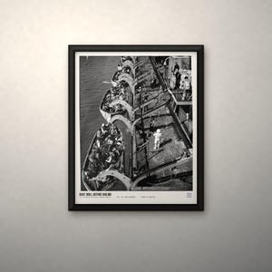 May include: A black and white framed print featuring an overhead view of a boat drill on a ship deck with lifeboats filled with people. The text at the bottom reads BOAT DRILL BEFORE SAILING, U.S. National Archives (1942), 80-G-3864-808038, FROM US ARCHIVES.